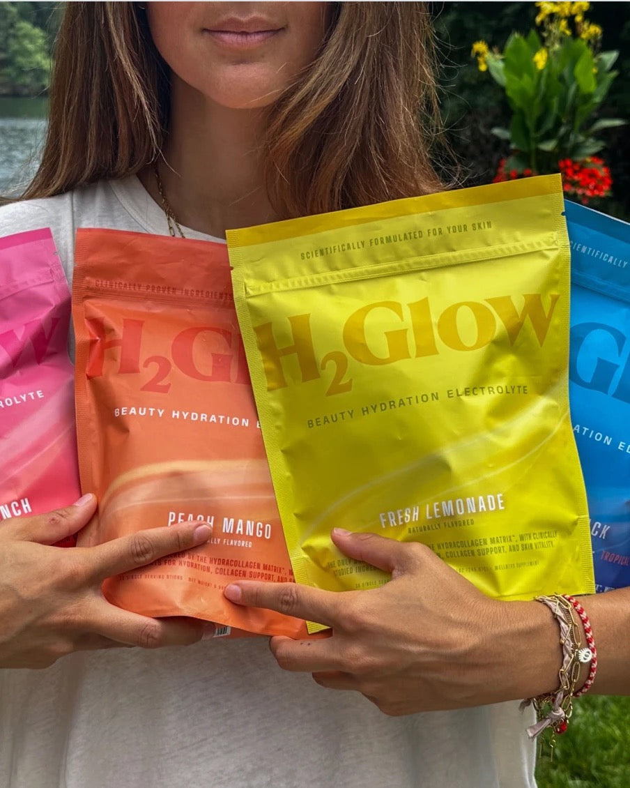 Four H2Glow Beauty Hydration Electrolyte pouches held up outdoors