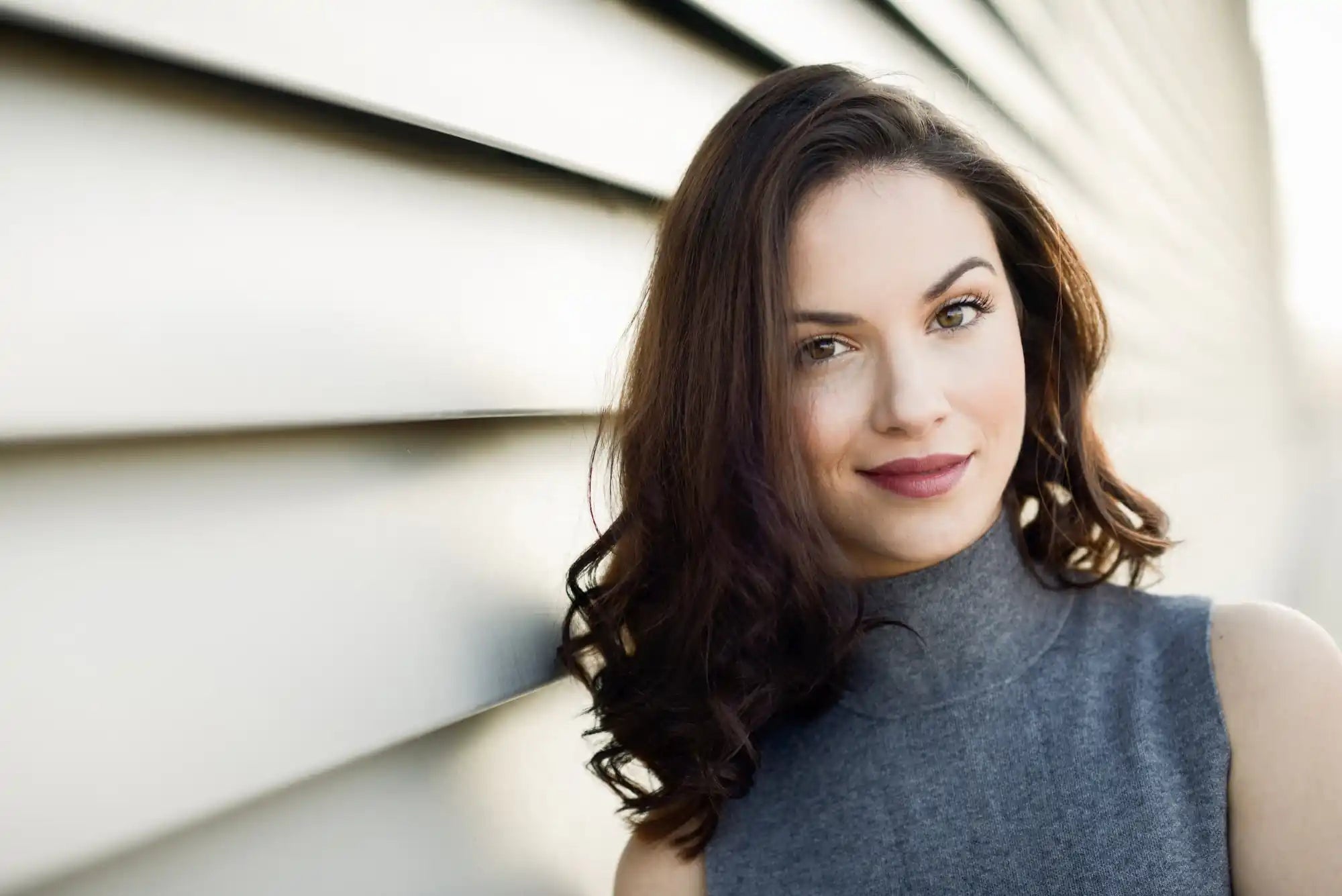 Woman in a close-up portrait with long dark hair, looking to the side, wearing a blue top.