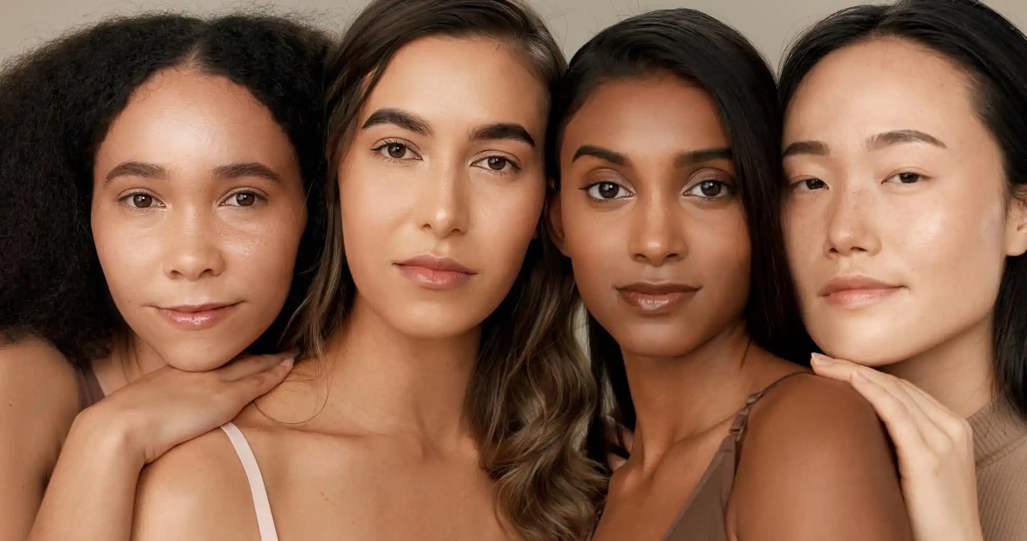 Four women close-up with smooth makeup and brown hair, facing the camera in soft neutral lighting